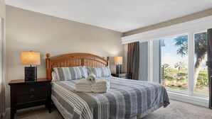 A hotel room with a bed, two bedside tables, a window with a view, and a carpeted floor.