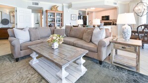 A living room with a beige sectional sofa, a wooden coffee table, and a decorative vase. - Spacious end condo w/large balcony & 3 beds, 3 baths! 🌴 (Destin)