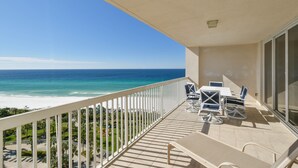A balcony with a view of the ocean, a table with chairs, and a glass door. - Spacious end condo w/large balcony & 3 beds, 3 baths! 🌴 (Destin)