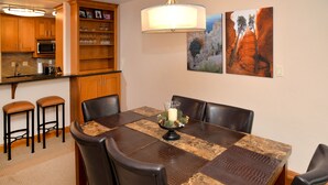 Un coin repas avec une table en marbre, des fauteuils en cuir, un lustre et des œuvres d’art accrochées au mur.