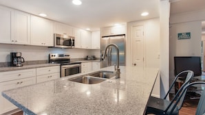 Una cocina moderna con armarios blancos, electrodomésticos de acero inoxidable y encimeras de granito.