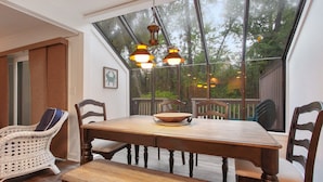Un comedor con mesa y sillas de madera, una silla de mimbre y un banco.