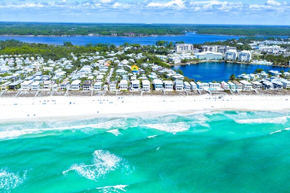 An aerial view of a coastal resort with beachfront properties, a sandy beach, and a large body of water.