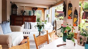 A cozy living room with a sofa, chairs, and a dining table. There are potted plants and artwork on the walls. - Inn Style Guesthouse (Cape Town)