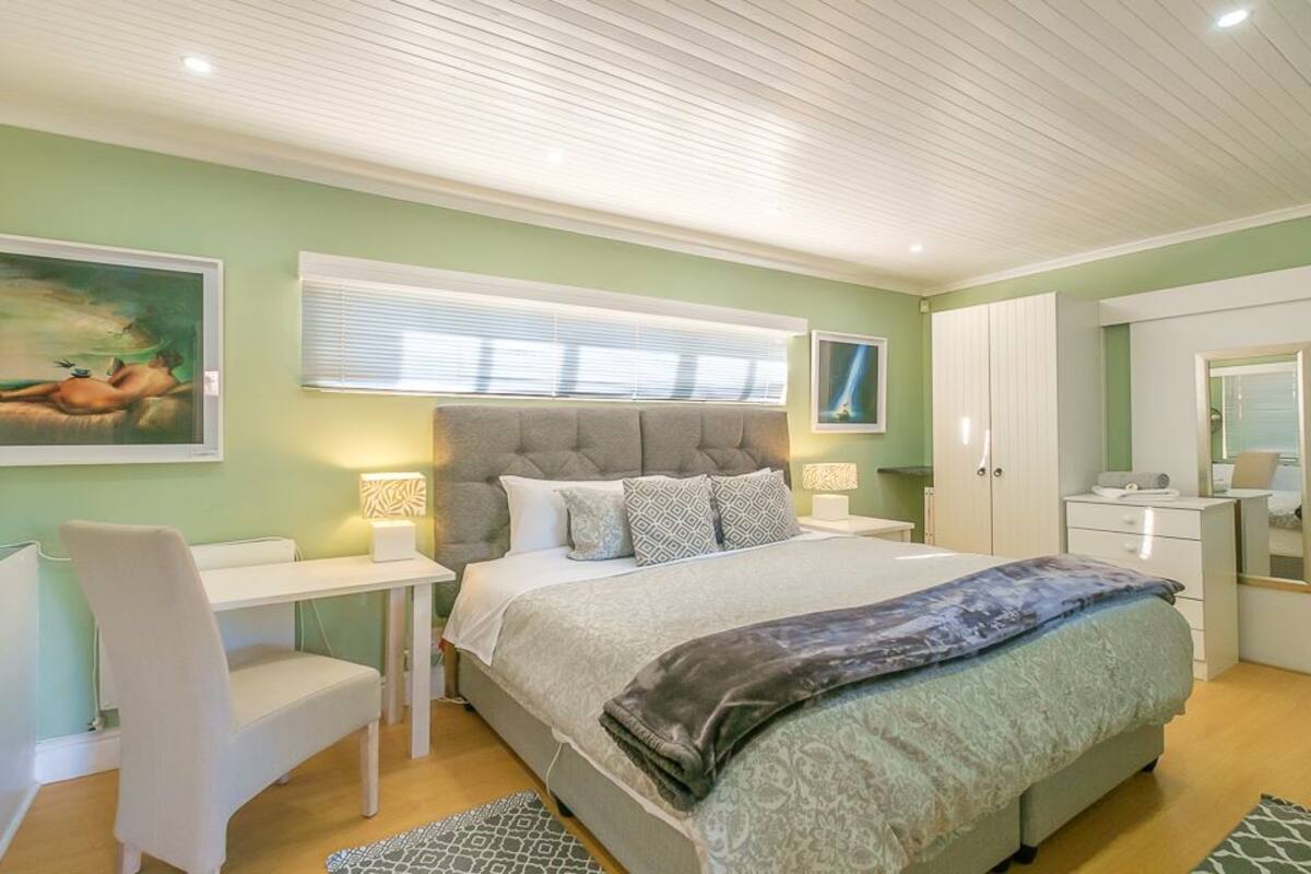 A bedroom with a bed, bedside tables, a desk, a chair, and a wardrobe.