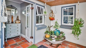 A room with a white door, a blue wall, a wooden ceiling, a white dresser, a mirror, a window, and a hanging plant. - Inn Style Guesthouse (Cape Town)