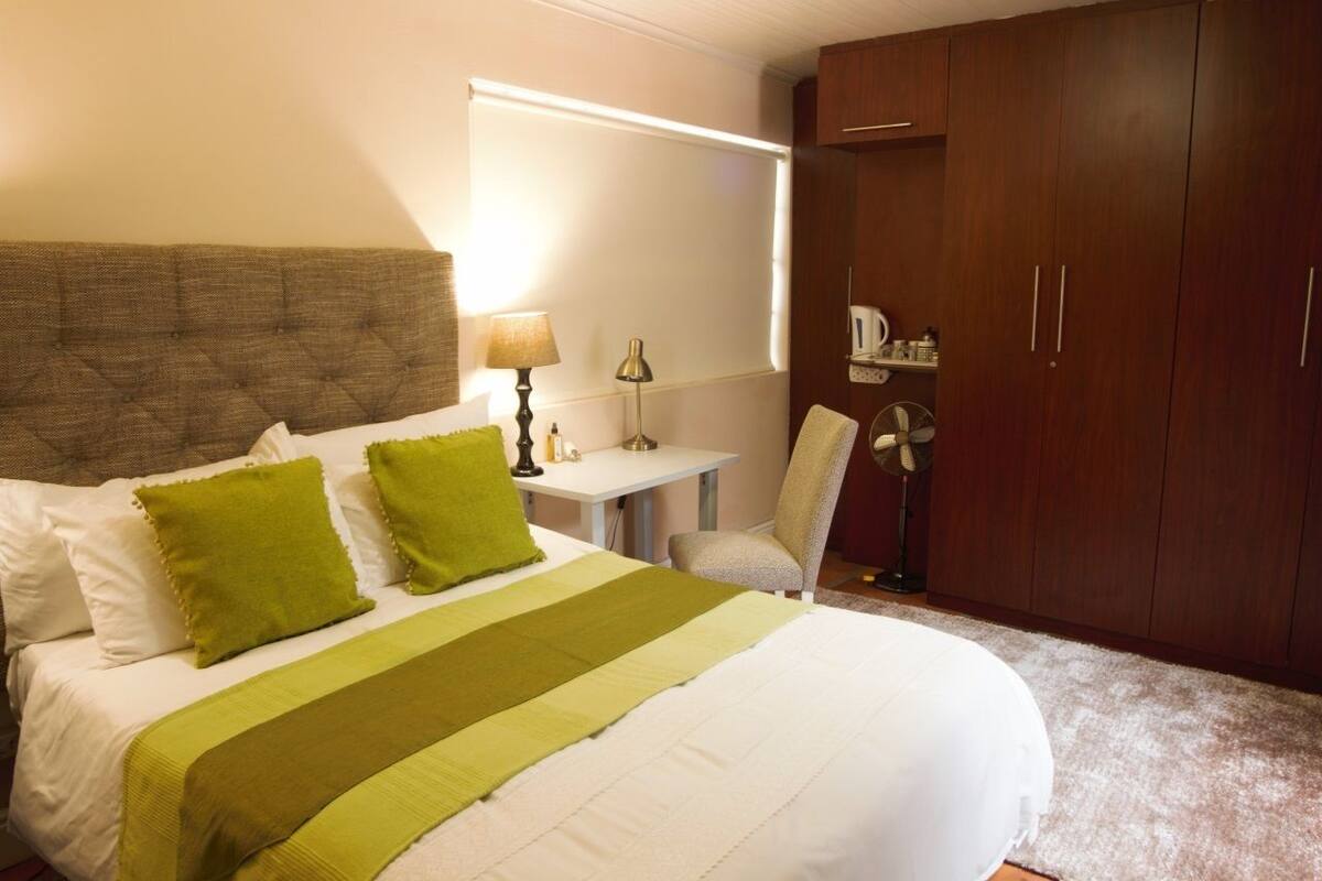 A neatly arranged bedroom with a bed, a desk, and a wardrobe.