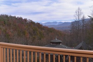 A cabin with a wooden deck and a view of a forested mountain range. - Cabin w/Stunning Mountain View-Hot Tub-Game Room (GATLINBURG)