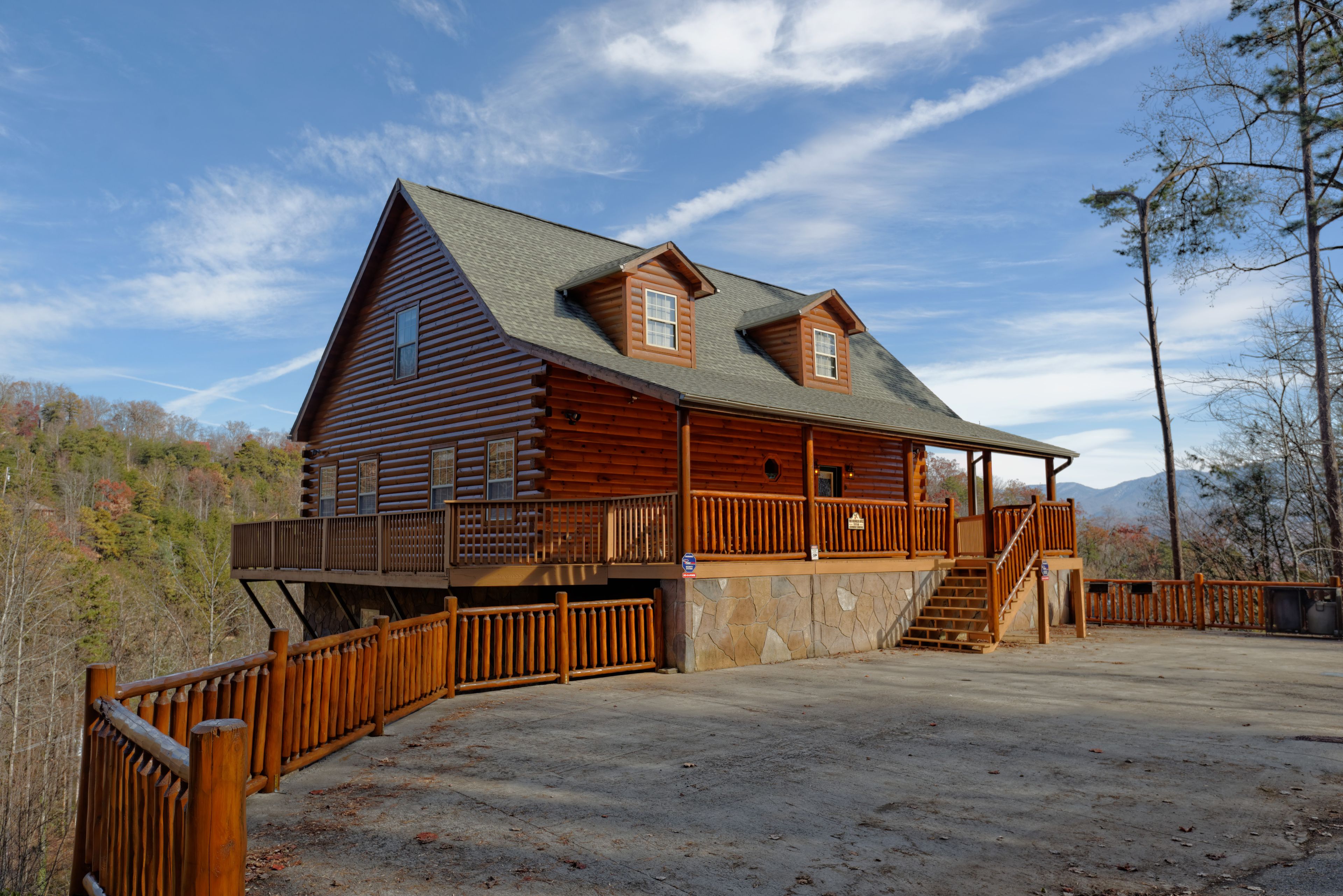 A log cabin with a balcony and a stone foundation.