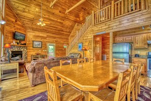A spacious wooden cabin with a large dining table, a cozy living area, a fireplace, and a kitchen with modern appliances. - Cabin w/Stunning Mountain View-Hot Tub-Game Room (GATLINBURG)
