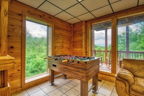A wooden-floored room with a foosball table and a sofa.