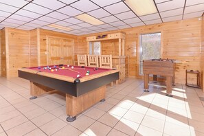 A pool table with balls, a wooden chair, and a wooden cabinet in a room with wooden walls and a tiled floor. - Cabin w/Stunning Mountain View-Hot Tub-Game Room (GATLINBURG)