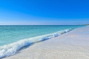 A beach with clear turquoise water and a sandy shore.