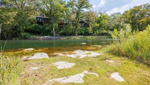 Une vue sur la rivière, avec un chalet en bois et un pont de pierre.