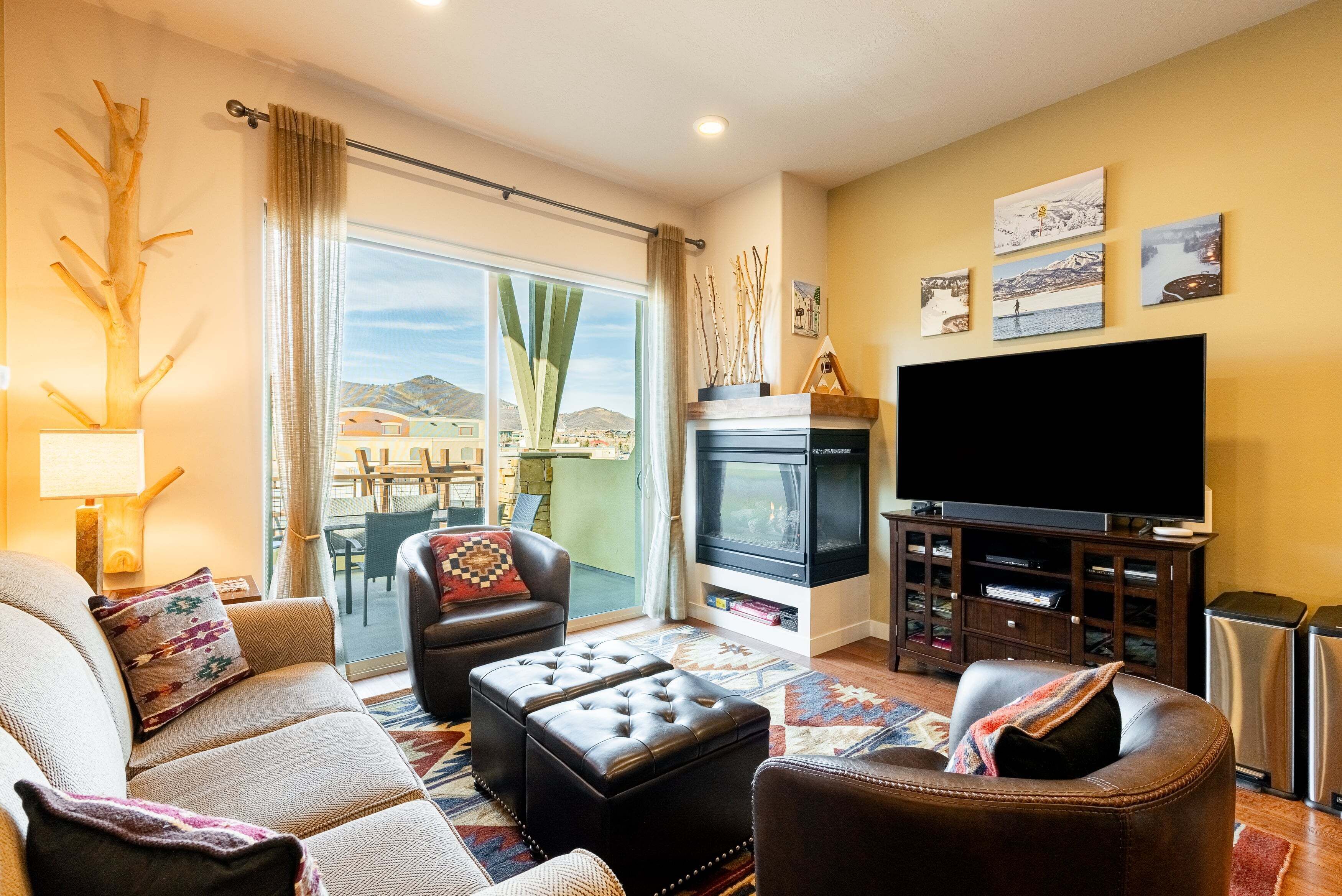 A living room with a sofa, ottoman, television, and fireplace.