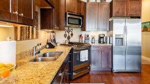A kitchen with granite countertops, stainless steel appliances, wooden cabinets, and a built-in microwave. - Bright and Airy Mountain Townhome. Walk to Shops, Dining, Trails + Hot Tub (Park City)