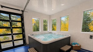 A hot tub with four steps, a window with a view of yellow foliage, and a basket of towels. - Spacious 7BR Lakeside Ski Lodge, Hot Tub, Game Room (Durango)