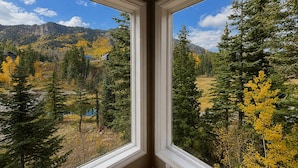A corner window with a view of a mountainous landscape, trees, and a small body of water. - Spacious 7BR Lakeside Ski Lodge, Hot Tub, Game Room (Durango)