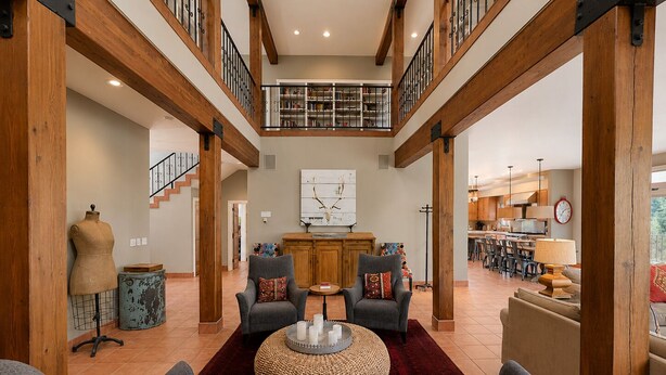 A spacious living area with a high ceiling, wooden beams, a staircase, and a view to the upper floor. - Spacious 7BR Lakeside Ski Lodge, Hot Tub, Game Room (Durango)
