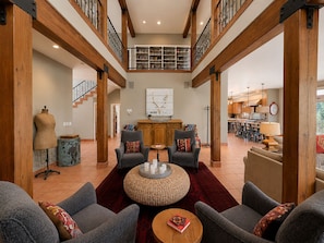A spacious living area with a high ceiling, wooden beams, a staircase, and a view to the upper floor. - Spacious 7BR Lakeside Ski Lodge, Hot Tub, Game Room (Durango)