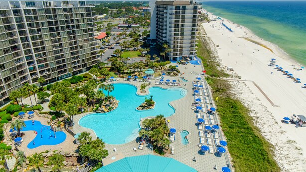 Ein Resort mit mehreren Swimmingpools, einem Strand und hoch aufragenden Gebäuden.