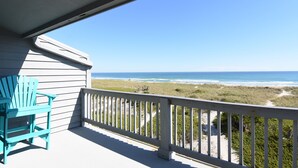 Een balkon met uitzicht op strand en zee.