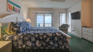 Een slaapkamer met een bed, een plafondventilator, een televisie, een stoel en een balkon met uitzicht.