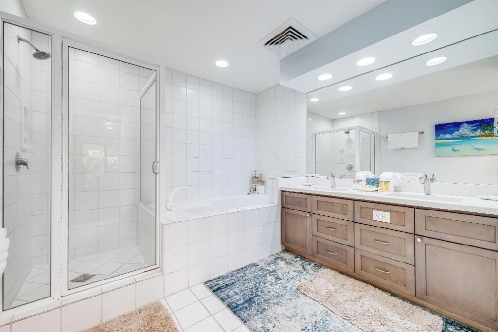 A modern bathroom with a glass shower enclosure, a bathtub, and a vanity with a large mirror.