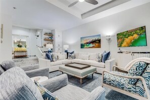 A modern living room with a sectional sofa, a coffee table, and a patterned armchair.