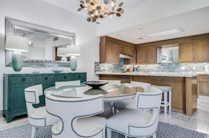 Une cuisine moderne avec un îlot central, des chaises blanches et un meuble de couleur turquoise.