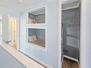 A hallway with a built-in bench with storage compartments, a door leading to another room, and a textured wall. - High 5! Mainsail Townhome! Dedicated covered parking Private Beach! FREE beach set up included. (Destin)