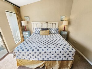 Une chambre à coucher avec un lit, deux tables de chevet, une fenêtre et une porte.