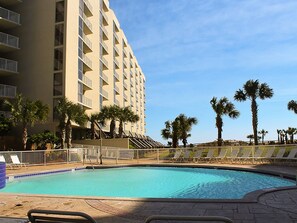 A hotel with a swimming pool, palm trees, and a clear sky. - High 5! Mainsail Townhome! Dedicated covered parking Private Beach! FREE beach set up included. (Destin)
