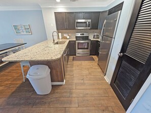 A kitchen with granite countertops, stainless steel appliances, and wooden flooring.