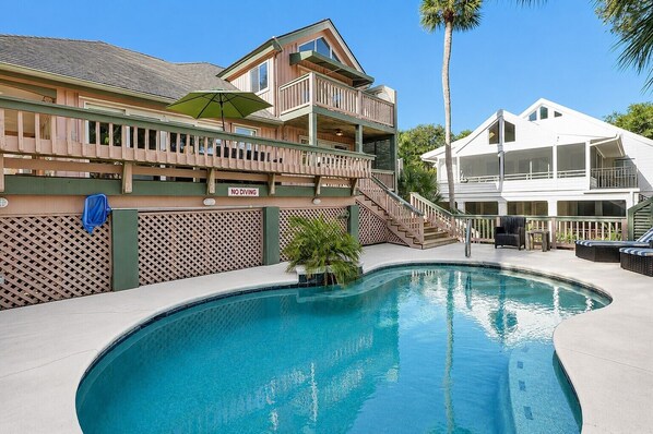 A pool area with a wooden deck, a 'NO DIVING' sign, and a two-story building with balconies.