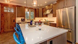 A modern kitchen with wooden cabinets, stainless steel appliances, and a marble island. - Relax in LUXURY! *Fantastic Discounts* Centrally located in the Resort! (Cle Elum)