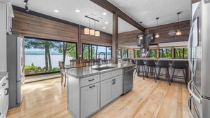 Une cuisine moderne dotée d’un grand îlot central, de tabourets de bar et offrant une vue sur le lac.