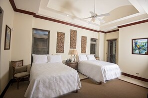 Quarto de hotel com duas camas, ventoinha no teto e obras de arte nas paredes.