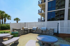 An outdoor patio with stone seating, a barbecue grill, and a large planter. - Open concept, private beach access w/resort amenities! 🏖️ (Destin)