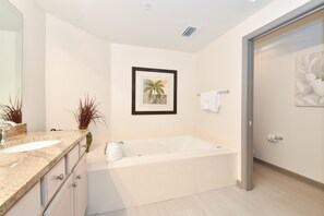 A modern bathroom with a large bathtub, a sink, and a mirror. There is a framed picture on the wall and a towel rack. - Open concept, private beach access w/resort amenities! 🏖️ (Destin)