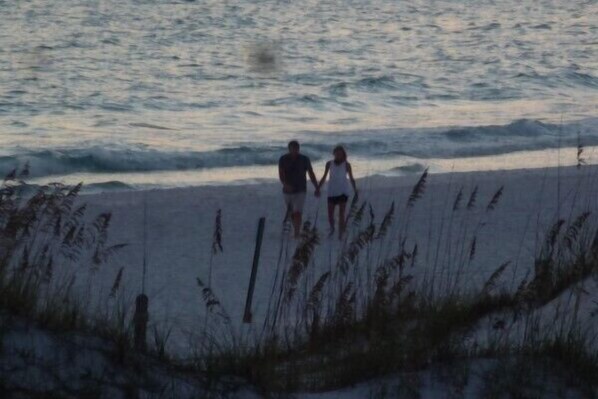 Two people walking on a beach with waves in the background.