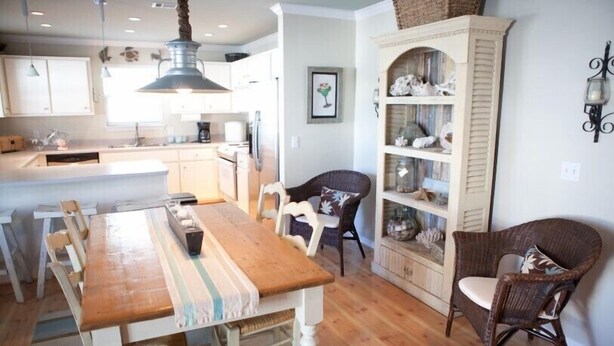 A kitchen with a wooden table, chairs, and a built-in cabinet with decorative items. - Gulf Winds Down 3/2 in Grayton, comm.pool, short walk to beach (Santa Rosa Beach)