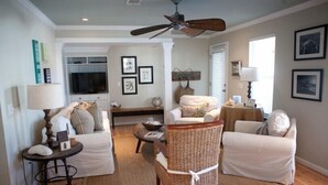 A living room with a sofa, two armchairs, a coffee table, a TV, and a ceiling fan. - Gulf Winds Down 3/2 in Grayton, comm.pool, short walk to beach (Santa Rosa Beach)