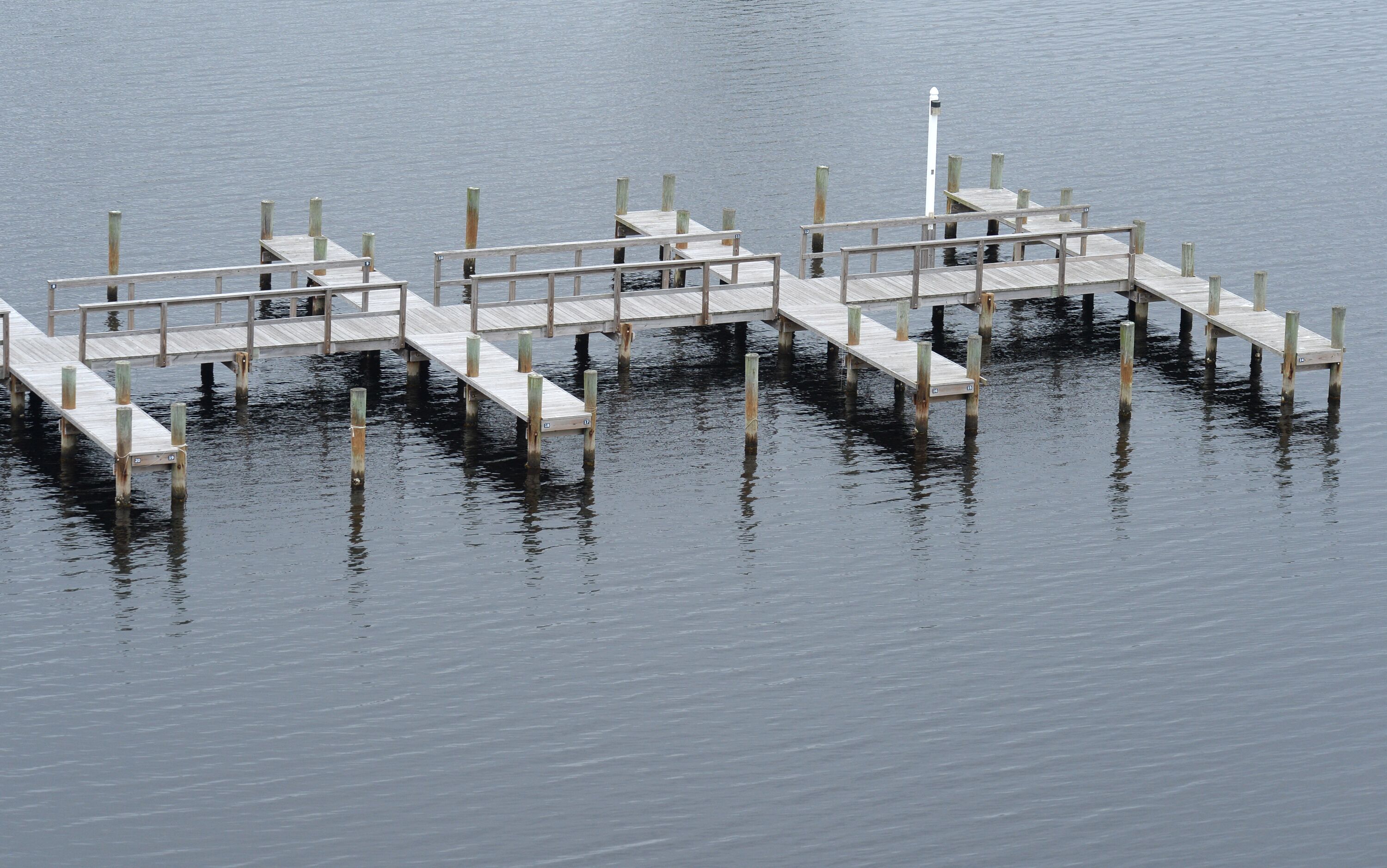 A wooden pier extending into calm water, with a lighthouse at the end.