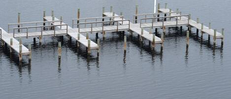 A wooden pier extending into calm water, with a lighthouse at the end.