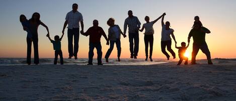 A silhouette of a family holding hands on a beach at sunset.