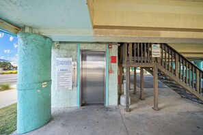 A private property entrance with a metal staircase leading up to a building. - Gulf Shores Condo for Two | Walk-to-Beach Location (Gulf Shores)