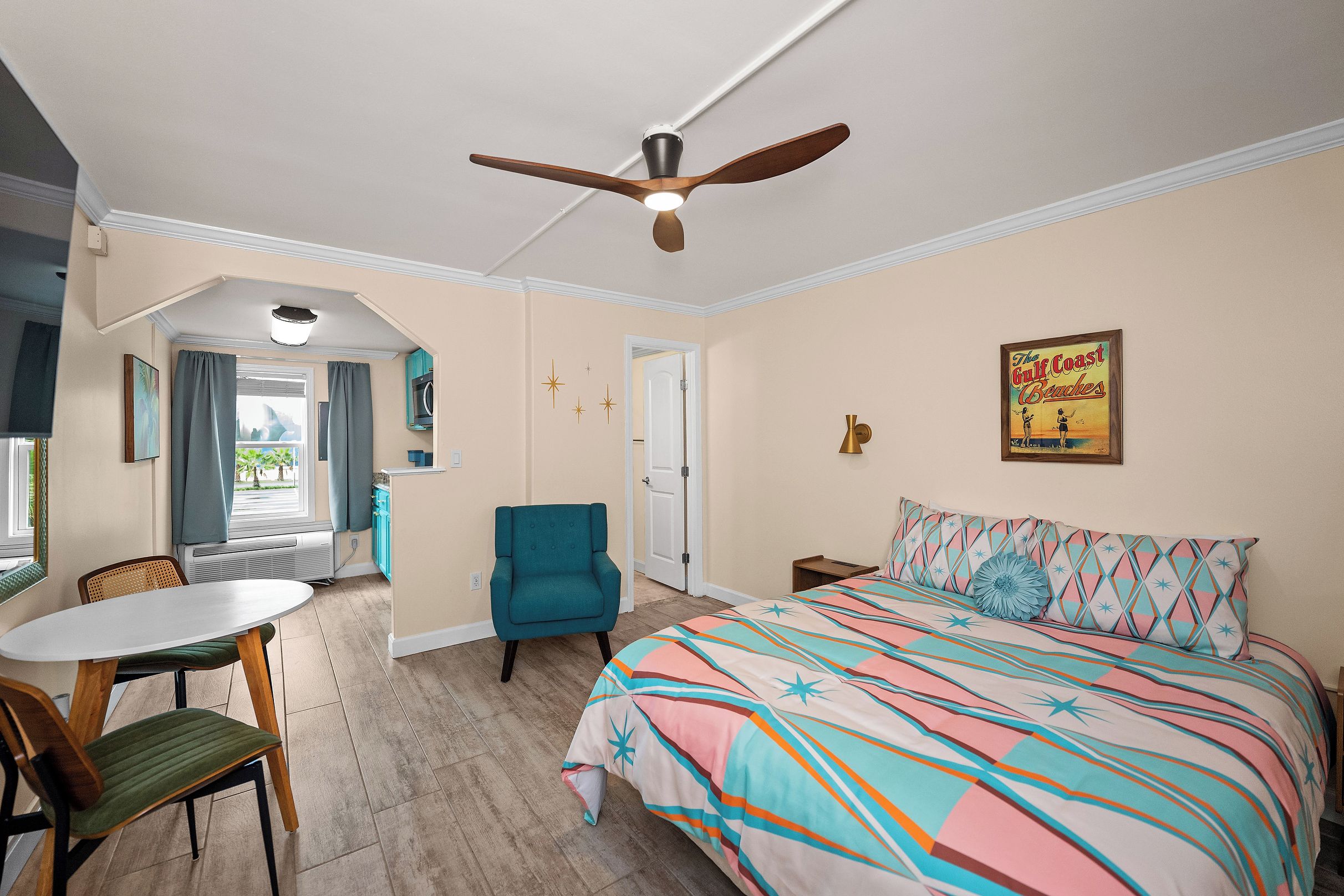 Ein Schlafzimmer mit Bett, Stuhl, Tisch und Deckenventilator.