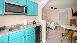 Cocina compacta con armarios turquesa, microondas, pileta y lavavajillas.