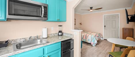 Une cuisine compacte avec des meubles turquoise, un four à micro-ondes, un évier et un lave-vaisselle.